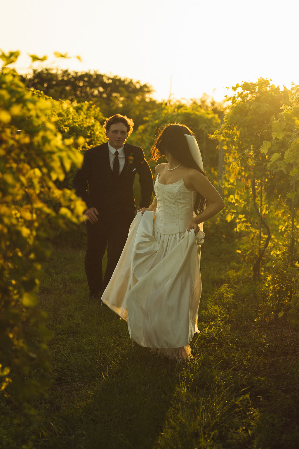 Wedding couple running through field during photos